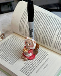Pen with a bear-shaped clip on an open book